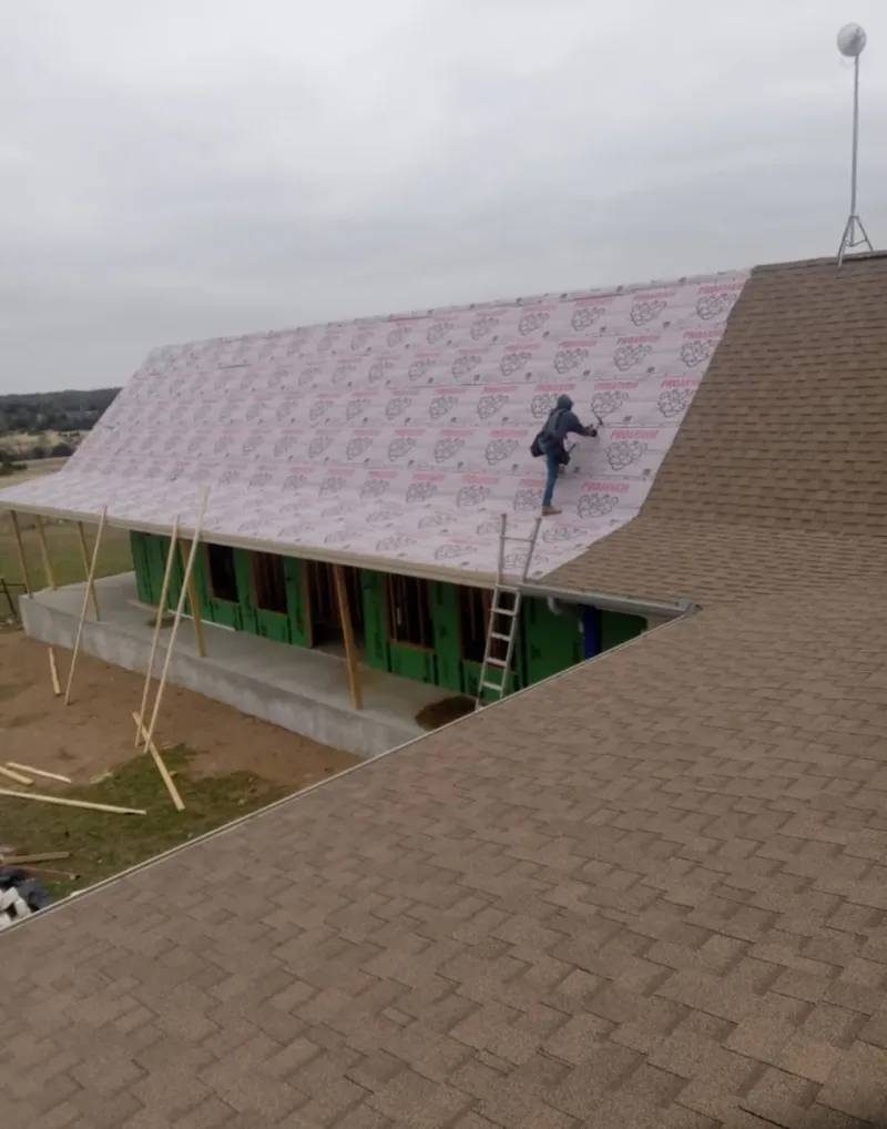 Worker preparing underlayment for a metal roof installation in El Centro